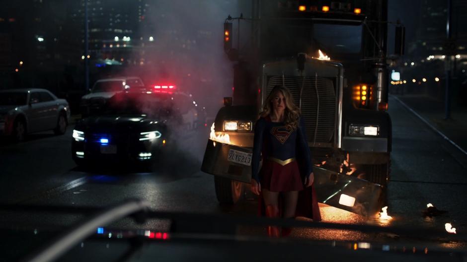 Kara walks towards the car after stopping the truck with her body.