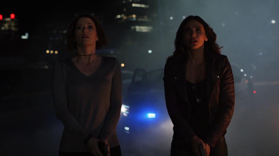 Alex and Maggie look up as Kara flies off.