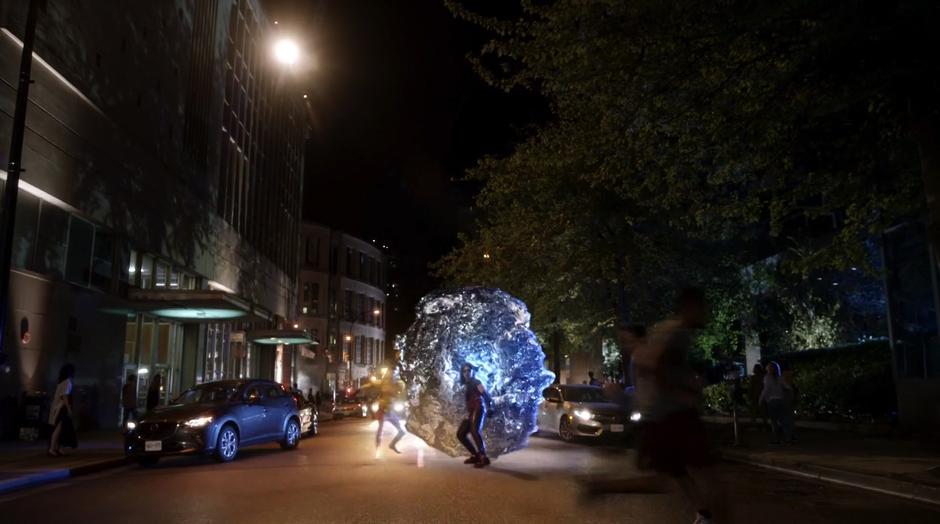 Wally and Cisco jump out of a portal as civilians run around in a panic.