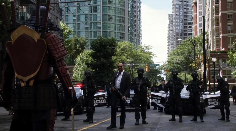 Joe walks up to the samurai while carrying a shotgun and the other police stand in a line behind him.