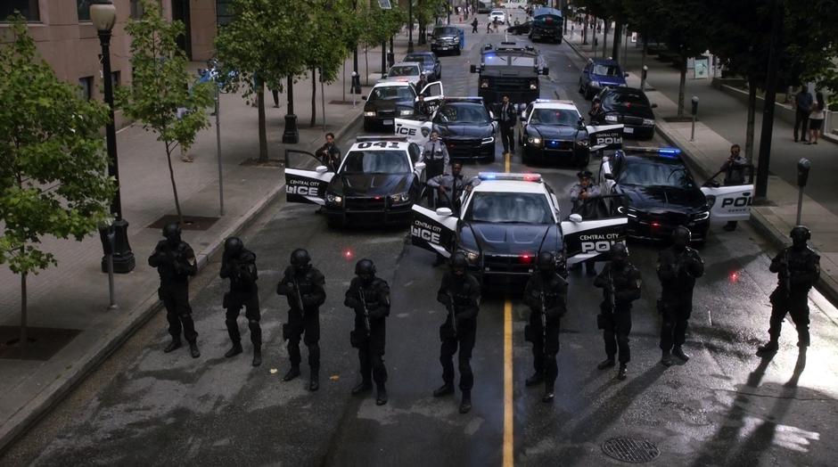 A bunch of police offices line up in the street to cover the samurai.