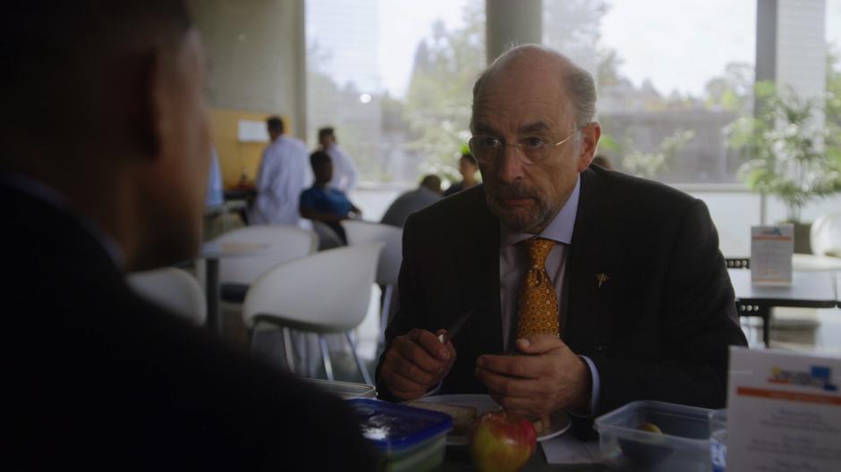 Dr. Glassman looks up as Dr. Andrews sits down at his table.