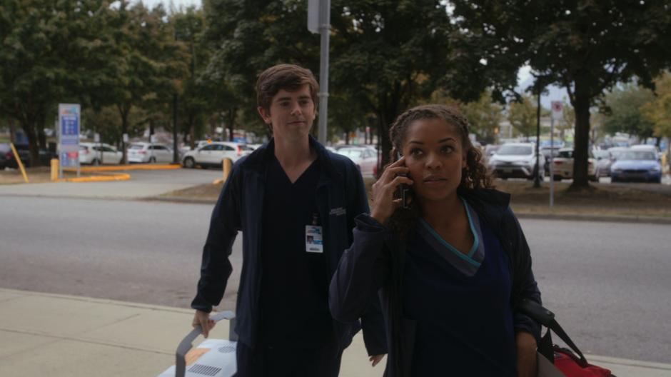 Shaun and Claire are walking up to the hospital with the liver while Claire is talking on the cell phone.