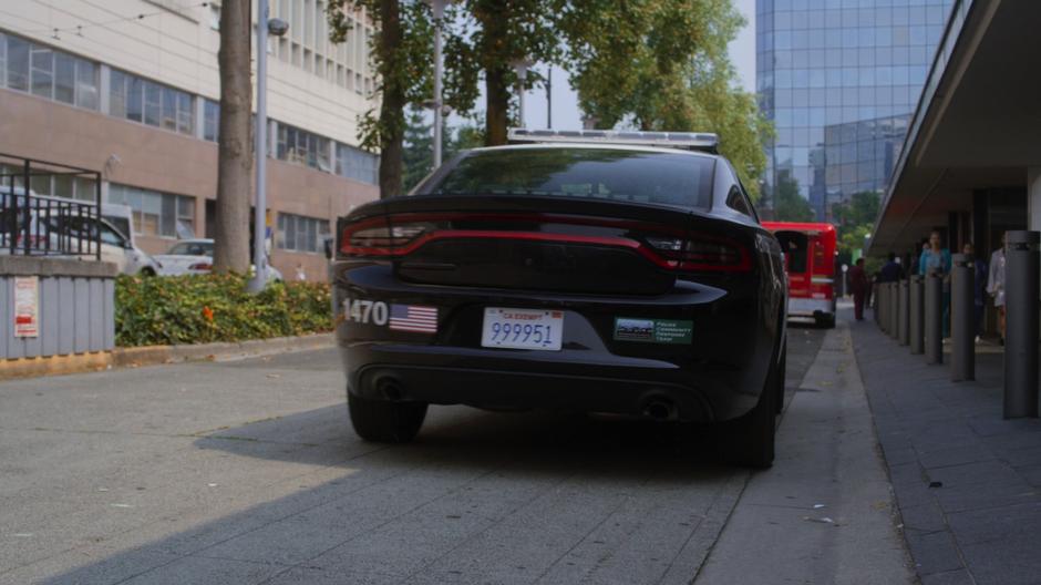 The police car drives away from the hospital.