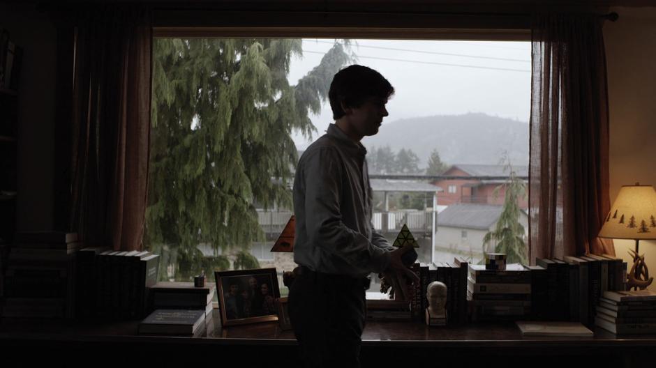 Shaun finishes packing up in front of the window of his house.