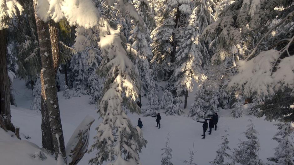 Joan and the goons point their guns at Ben Rivers while Maze enters the clearing from the woods.