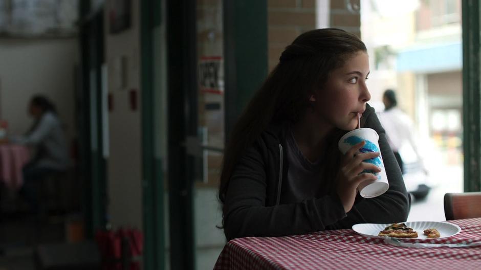 Ruby drinks from her soda while watching the hubbub build outside.