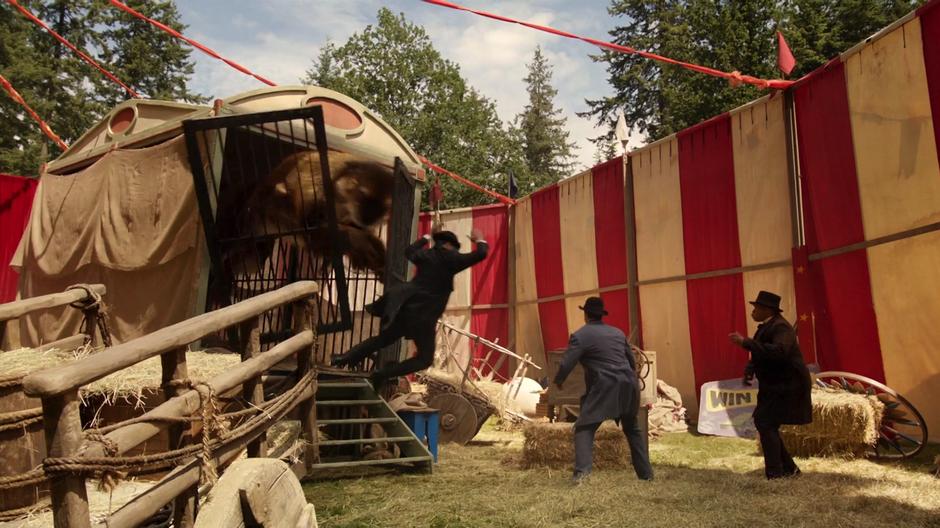 Nate is throw back as the sabertooth tiger bursts out of its cage and jumps towards Ray and Jax.