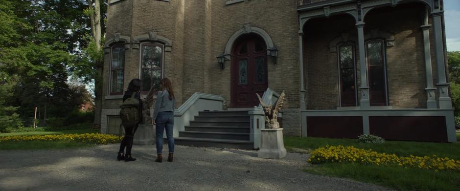 Laura starts to lead the way up to the front door of the mansion.