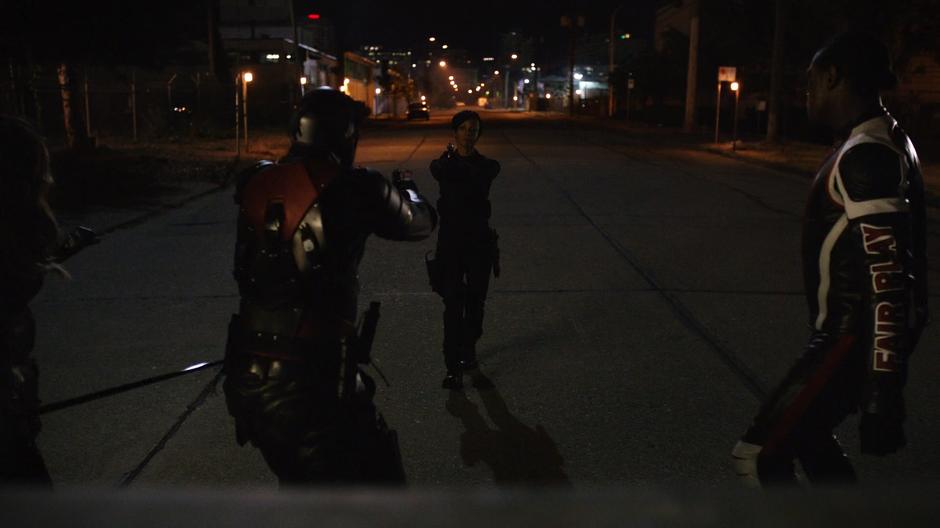 Onyx points her gun at Dinah, Rene, & Curtis behind the truck.