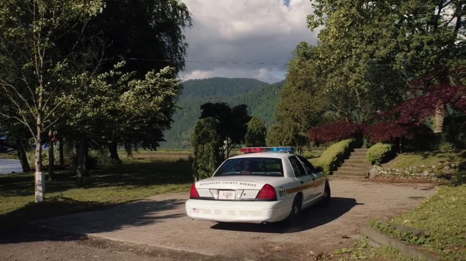 The police car pulls up to the front of the house.