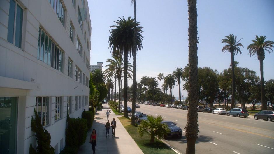 Chloe and Lucifer walk down the street towards the hotel.