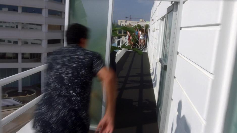 The suspect runs along the side of the hotel towards a locked gate.