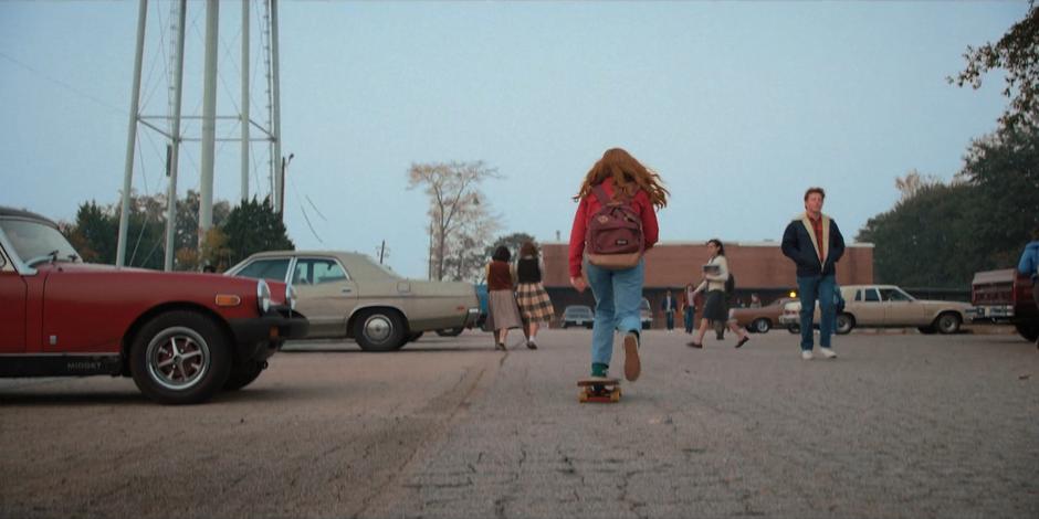 Max skates across the parking lot up to the school.