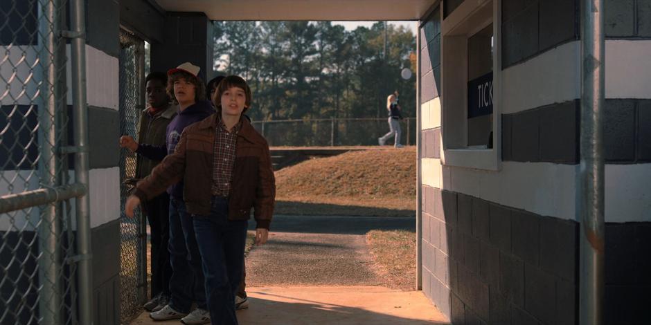 The boys turn and follow Max as she goes up to the school building.