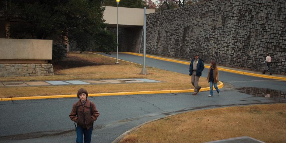 Will leads the way back to the car as Hopper and Joyce chat behind him.