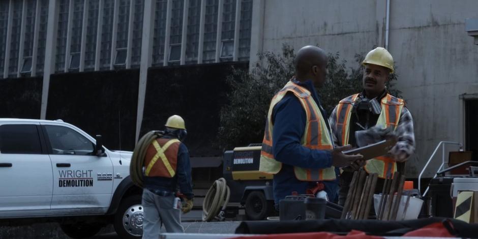 One of the workers approaches another about some flooding going on in the building.