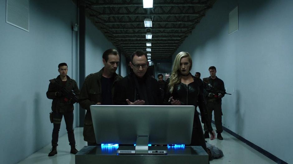 The goon, Cayden James, and Black Siren prepare to use the stolen fingerprints on the door scanner.