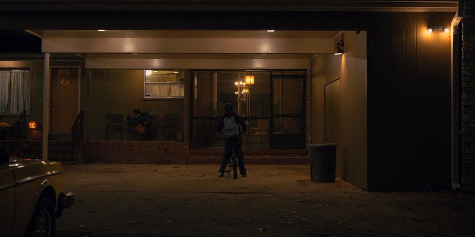 Dustin parks his bike in front of his house in the evening.