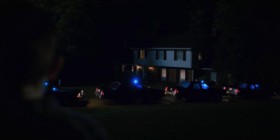 Eleven looks down from the hill and sees the police surrounding the house.