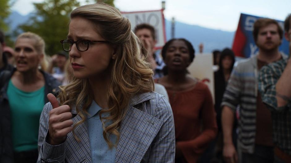 Kara gives Lena the thumbs up from where she stands in the angry crowd.