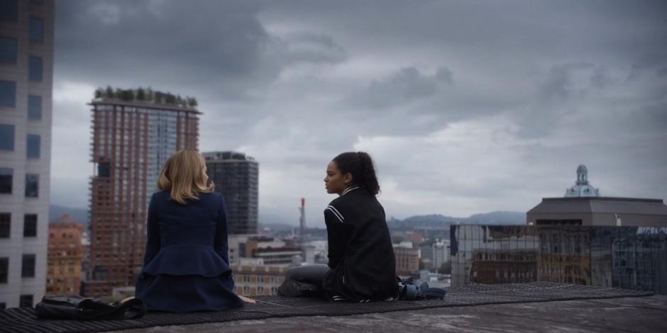 Marcy and Carly sit on a air handler atop the building and talk.