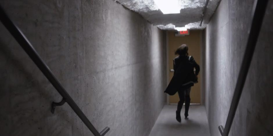 Carly arrives at the ground floor and runs to the exit door.