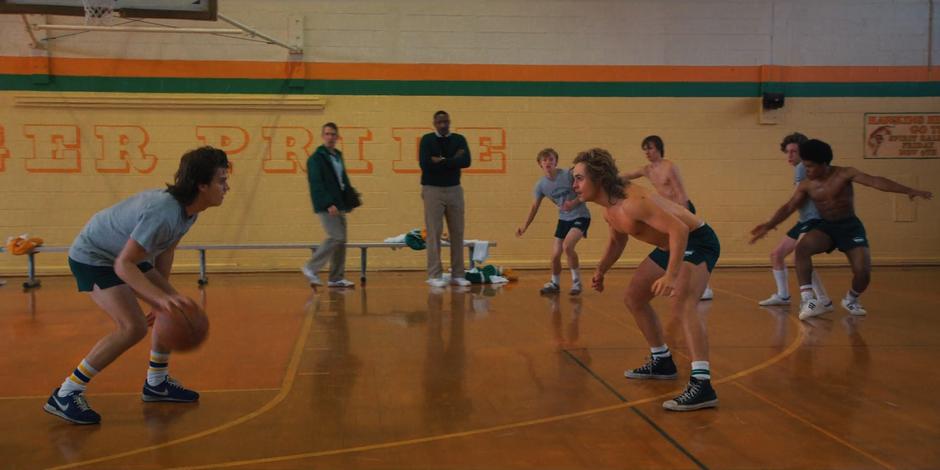 Steve and Billy face off on the court during basketball practice.