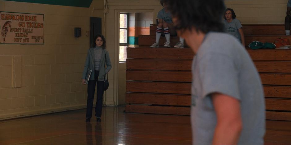 Nancy gets Steve's attention from the edge of the gym.