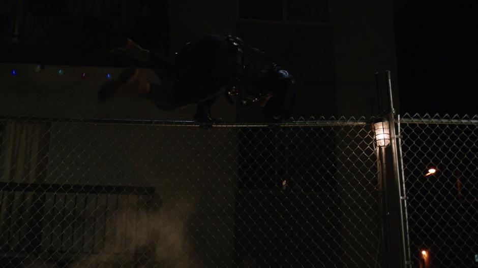 The Vigilante jumps over a fence after taking off his mask.