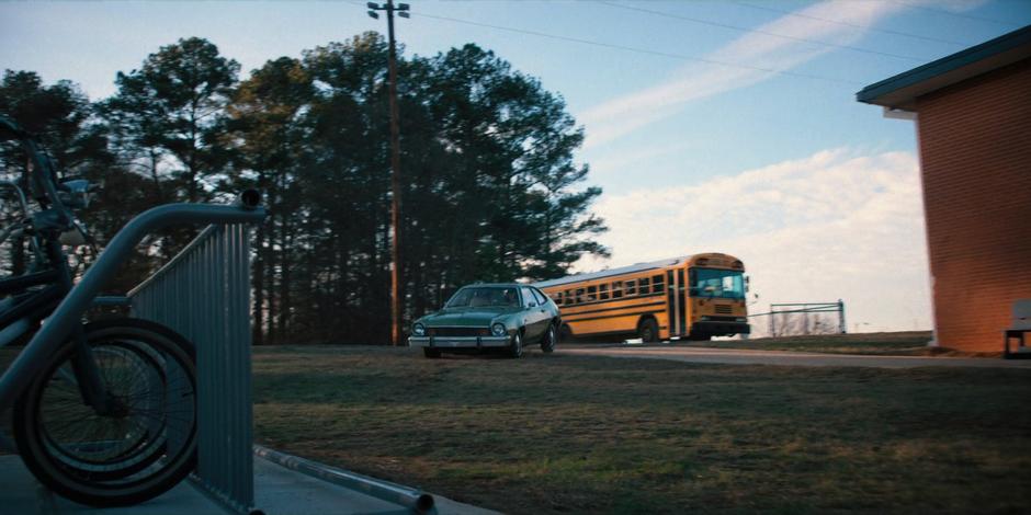 Joyce drives her car onto the lawn in front of the school.