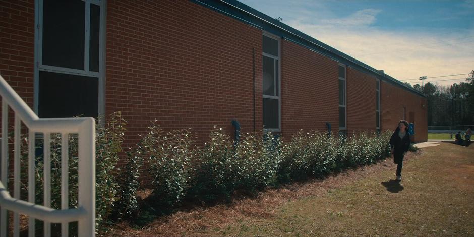 Mike runs around to the front door of the school.