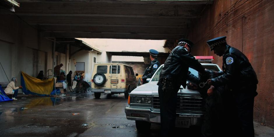 The gang's van drives down the alley as the police arrest someone.