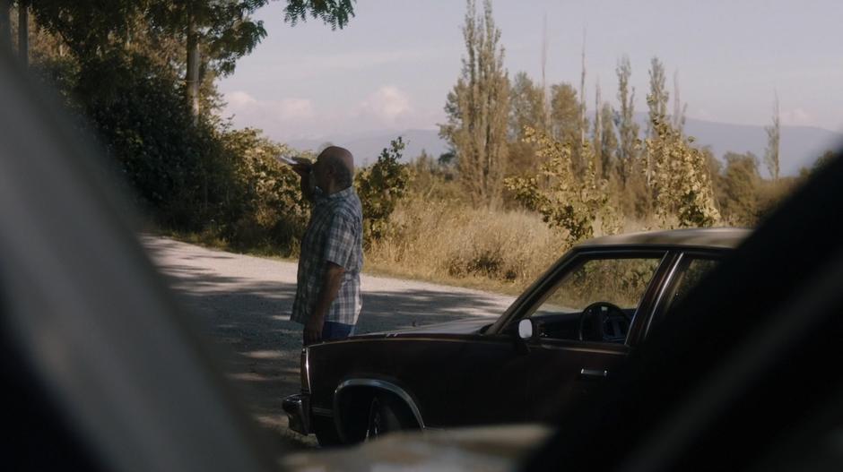 Arnold Cardenas takes a swig of alcohol while staring up at his old childhood home.