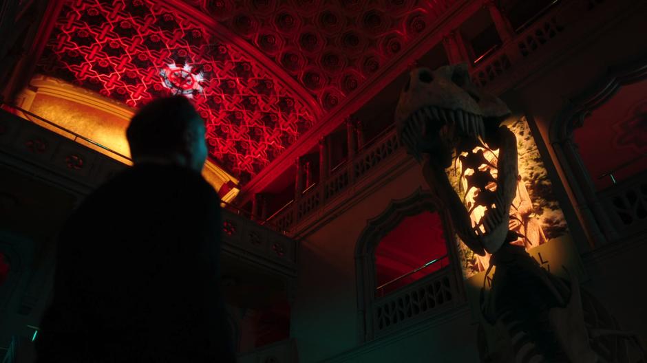 The museum guard looks up at the animated dinosaur skeleton that roars over his head.