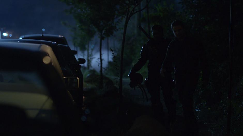 Slade and Oliver walk down the side of the dark street.