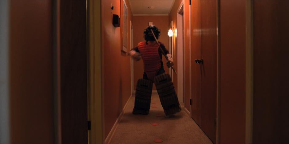 Dustin runs down the hallway in heavy padding after leaving a trail of meet on the ground to lure Dart.