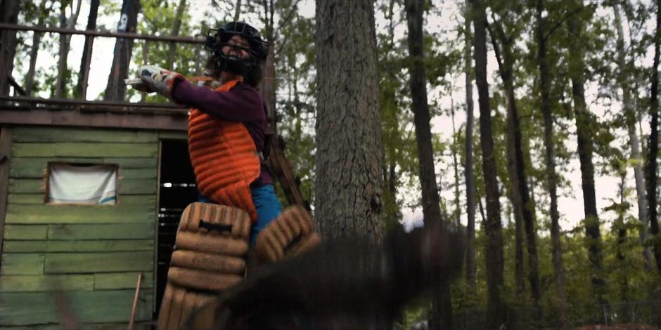 Dustin runs at Dart with a hockey stick while wearing heavy padding to scare the creature down into the cellar.