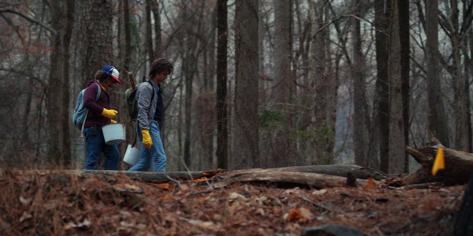 Dustin and Steve walk down the tracks past one of the marker flags left by the Hopper's team.