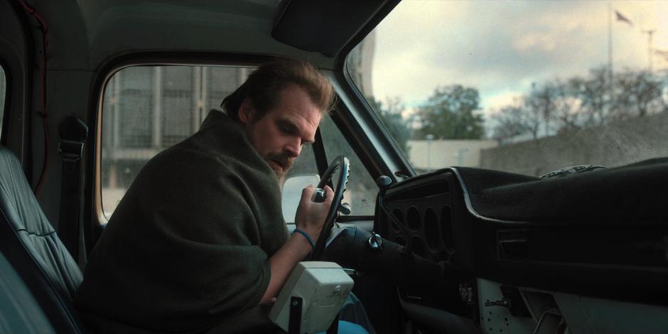 Hopper calls for Eleven over the radio in his truck.