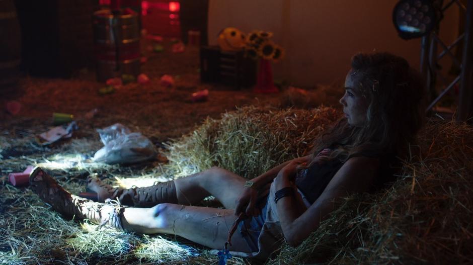 Suzie lies against a pile of hay while holding the wand.