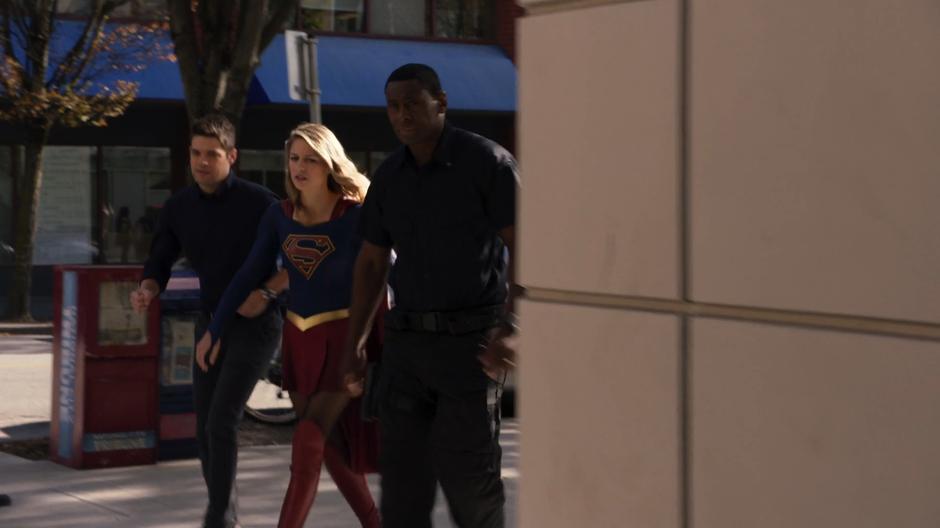 J'onn leads Kara and Winn around the corner into the alley.