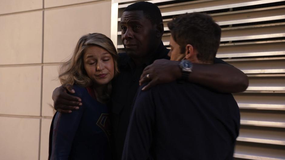 J'onn hugs Kara and Winn close as he prepares to phase them down to the ship.