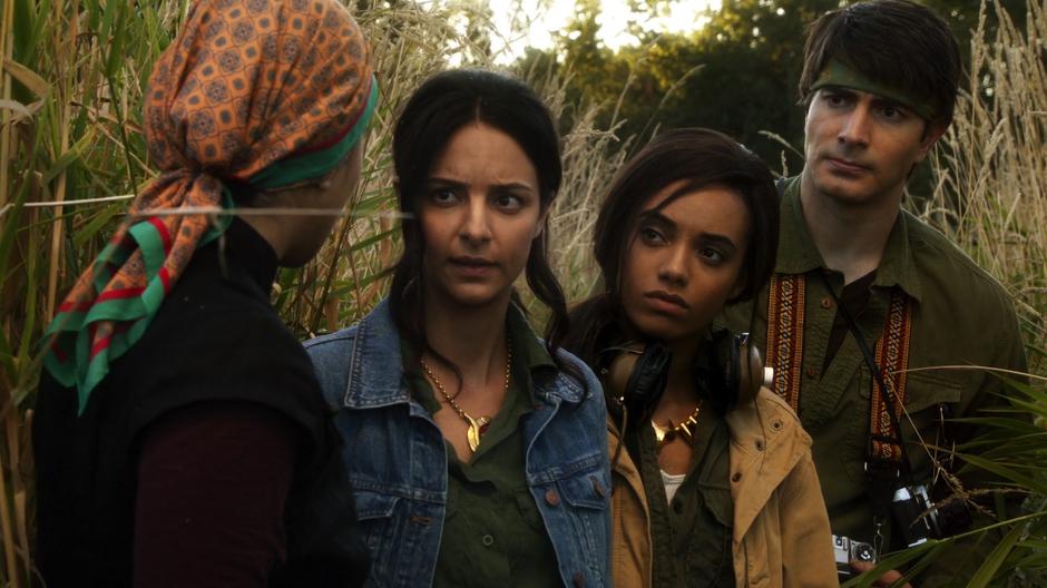 Anh Ly talks to Zari, Amaya, and Ray as she leads them to the camp in the woods.