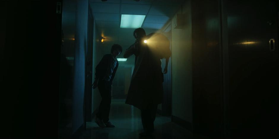 Hopper leads the way out of the security room carrying Will as Mike follows him.