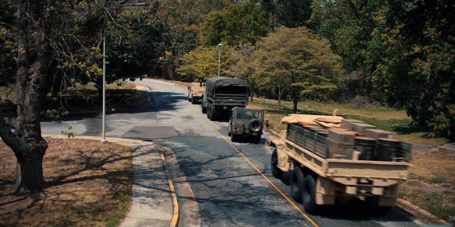 A jeep joins a convoy of several military vehicles heading away.