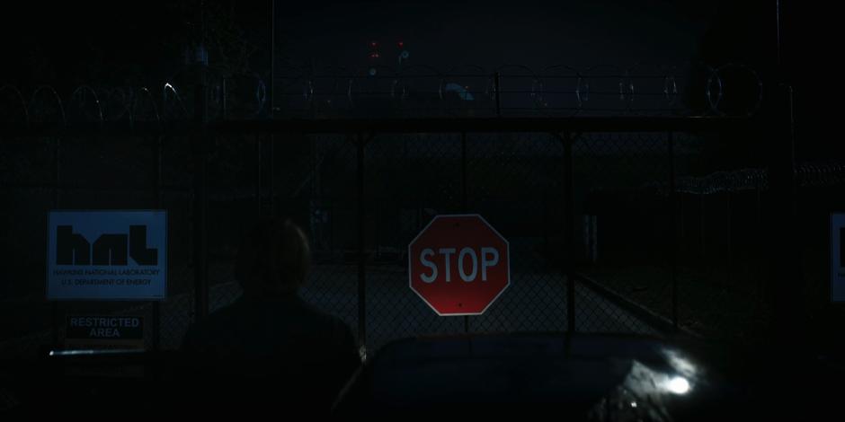 Jonathan looks through the gate at the darkened building.