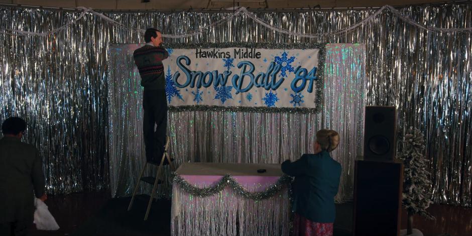 Mr. Clarke hangs up a Snow Ball poster before the dance.