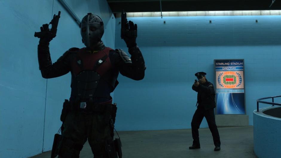 Rene holds up his hands as a fake police officer holds a gun to his back on the side ramp.