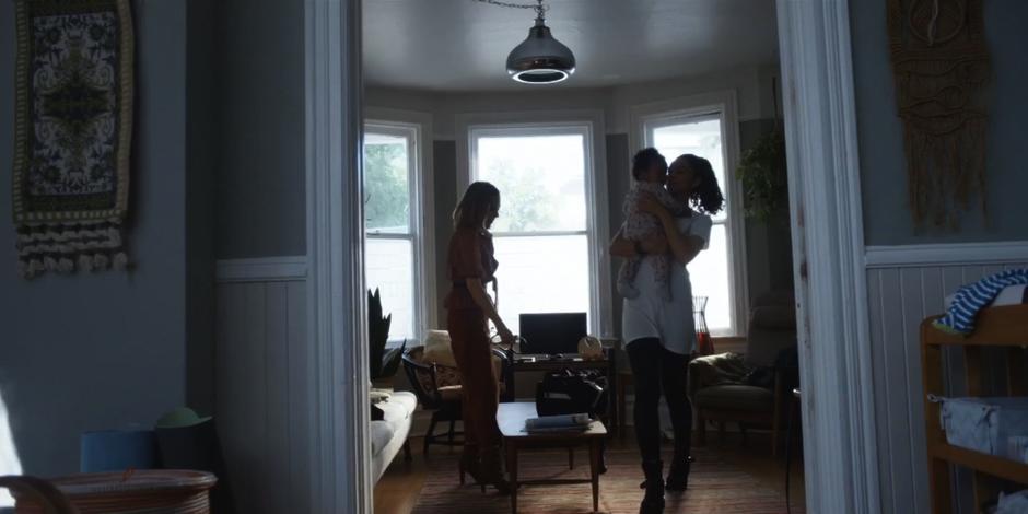 Carly holder her kid in her arms while Marcy packs up her medical kit.